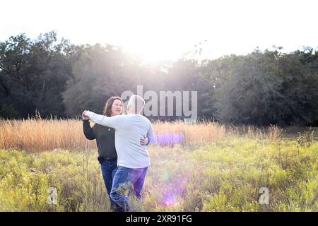 Couple dancing in a field with the sun shining brightly in the b Stock Photo