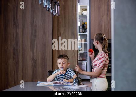 Beautiful mother helping son doing schoolwork at home Stock Photo