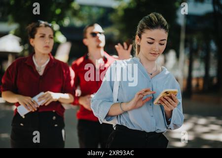 Young businesspeople using smart phones outdoors in the city on a sunny day Stock Photo