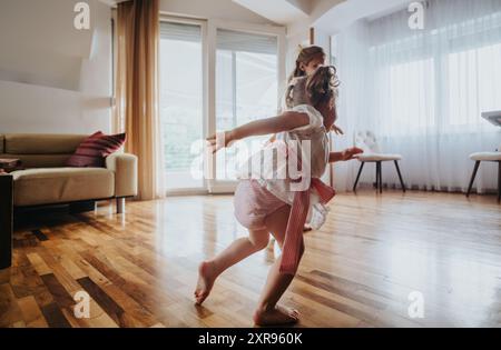 Two kids playing and dancing in a cozy living room with natural light Stock Photo