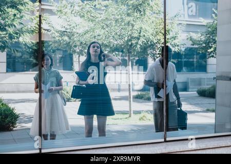 Group of diverse professionals seen through window waiting outside an office building Stock Photo