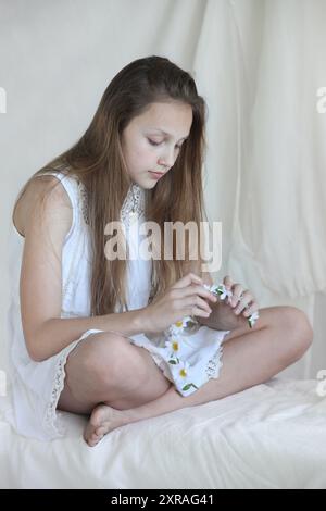 pretty  blond preteen girl in white dress with chamomile flower wreath Stock Photo