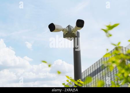 CCTV camera, Two high-definition security cameras are mounted on a pole in front of a bank. The cameras are positioned to capture clear images of peop Stock Photo