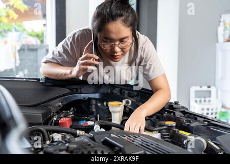 A woman mechanic performs engine maintenance on a car in an auto repair garage, using tools to change the engine and provide essential automotive serv Stock Photo