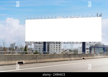 Empty billboard on the side of a highway. The billboard is located in a city, and it is facing the highway. The billboard is large and rectangular. Ba Stock Photo