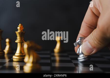 Knight black chess piece on chessboard. The hands of a businessman move a chess figure in a successful tournament played. Management strategy or leade Stock Photo