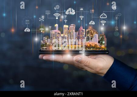 Smart city technologies concept with digital tablet and night megapolis city skyscrapers with digital cloud icons on human hand at blurry skyline back Stock Photo