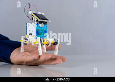 A plastic robot is in the hand of a student placed on the table, experimenting with learning with his hands, improving his skills. School writes code Stock Photo