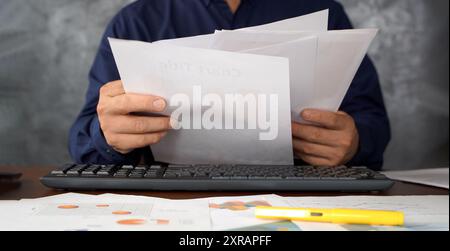 Focused businessman reviewing paper reports, received letter, notice from bank, working at office workplace with laptop. Legal expert, professional, l Stock Photo