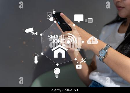 Woman's hands holding smartphone in bedroom with couple exposure of smart home interface, automation concept. Smart home automation control system. In Stock Photo