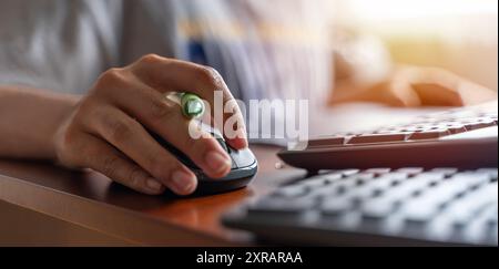Closeup shot of a mouse holding a female hand and working with a desktop computer while sitting at a desk. Human hand on a notebook computer mouse on Stock Photo
