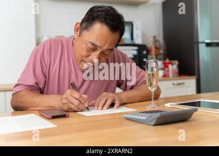 Portrait of handsome man sit on sofa arm on chin look interested notebook write down notes list to do indoors. Close Up of a senior man writing a lett Stock Photo