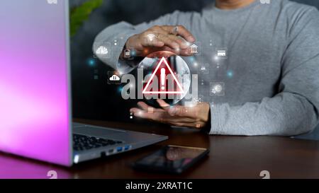 Young business man hand using smartphone, laptop with warning sign for error notification and maintenance concept.  Malicious software,virus and cyber Stock Photo