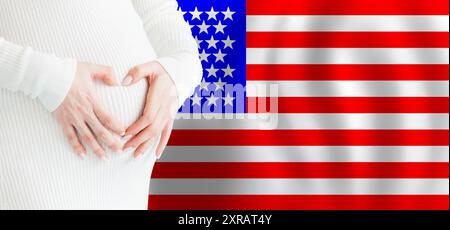 Demographics, pregnancy and love baby in USA concept. Pregnant woman making heart against her stomach on American flag background. Stock Photo