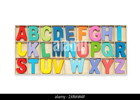 Colorful alphabet, wooden uppercase letters placed in a box, white isolated background. Stock Photo