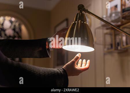 Replace ordinary light bulbs with LEDs at home. LED light Power saving concept. Asia man changing compact, fluorescent (CFL) bulbs with new bulb. Stock Photo