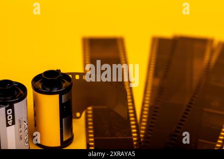 Close-up shot of analog film rolls with developed film laid out on a bright yellow surface. A tribute to vintage photographic Stock Photo