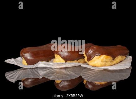 Three eclairs with cream, macro, isolated on a black background. Stock Photo