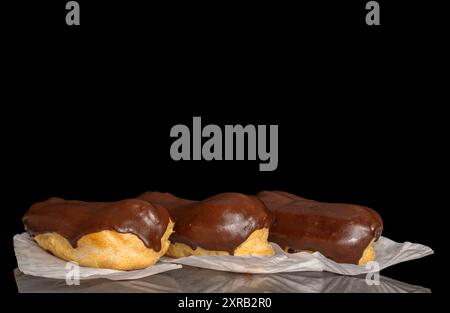 Three eclairs with cream, macro, isolated on a black background. Stock Photo