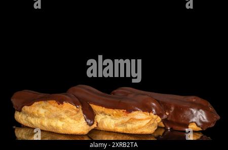 Three eclairs with cream, macro, isolated on a black background. Stock Photo