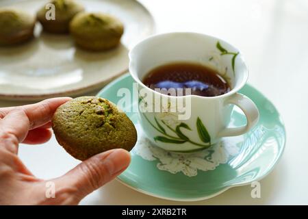 Woman enjoying tea time with matcha green tea cake and black tea Stock Photo