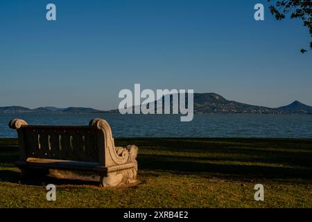 Scenic landscape with a stone bench in coast of Lake Balaton in Fonyod city. Balaton Uplands is on the background. Included the Tanu hegyek too Stock Photo