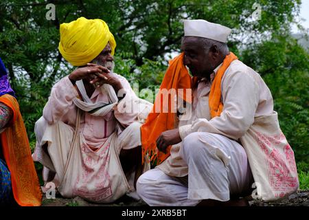 Pune, Maharashtra, India, 2 July 2024, Pilgrims or warkari with saffron flags participate in religious procession during Pandarpur yatra on the road D Stock Photo