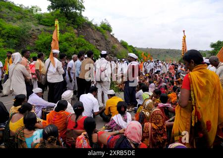 Pune, Maharashtra, India, 2 July 2024, Pilgrims or warkari with saffron flags participate in religious procession during Pandarpur yatra on the road D Stock Photo