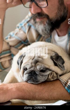 Tired man work at home on laptop computer in online digital modern job - concept of smart working people lifestyle - people and dog couple indoor best friends forever and affection concept Stock Photo