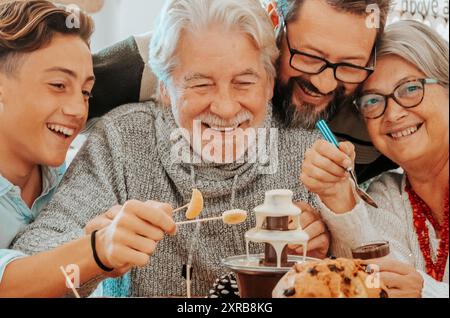 Family group celebrate together christmas lunch at the table eating and having fun in friendship. Mixed ages men and woman people enjoying holiday xmas eve at home. Young and senior generations Stock Photo