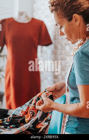 Seamstress at home workshop working with clothes in fashion industry. Professional tailor making dress. Side view of woman in hobby and leisure activi Stock Photo