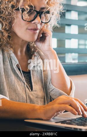 Attractive woman working on laptop at the desk in coworking place or modern office. Modern trendy businesswoman using computer alone for online job. P Stock Photo