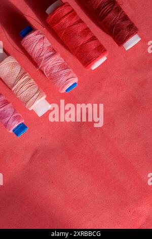 Spools of different colors are arranged in a row on a pink background. In the style of flat lay. Stock Photo
