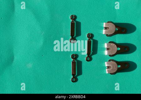 Sewing hooks laid out in a row on a turquoise background. In the style of flat lay. Stock Photo