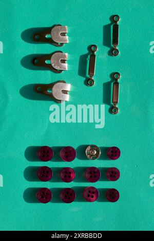 Buttons and hooks are arranged in a row on a turquoise background. In the style of flat lay. Stock Photo