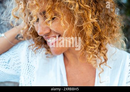 Close up portrait of real adult woman smiling and enjoying time. Curly long hair blonde female enjoying outdoor leisure activity and have nice happy t Stock Photo