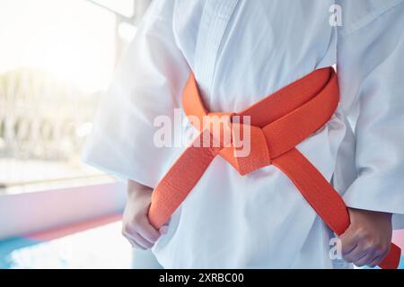 Martial arts, belt and student in studio for fitness, training and fight with orange bow and discipline. Girl, kung fu and ready in dojo as workout Stock Photo