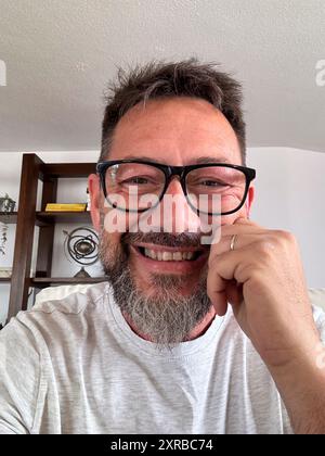 Head shot portrait of happy boomer 50s man in casual making video call from home couch, looking at camera, smiling, speaking at webcam, attending online chat, virtual conference. Screen view Stock Photo