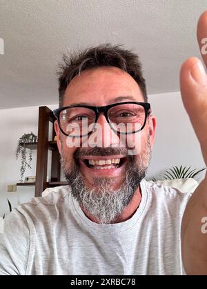 Head shot portrait of happy boomer 50s man in casual making video call from home couch, looking at camera, smiling, speaking at webcam, attending online chat, virtual conference. Screen view Stock Photo