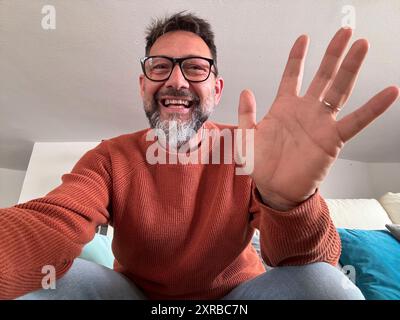Head shot portrait of happy boomer 50s man in casual making video call from home couch, looking at camera, smiling, speaking at webcam, attending online chat, virtual conference. Screen view Stock Photo