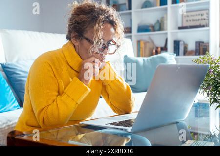 Side view concentrated pleasant mature adult woman looking at computer screen. Happy middle aged lady web surfing information, ordering food online, chatting in social networks, playing game. Stock Photo