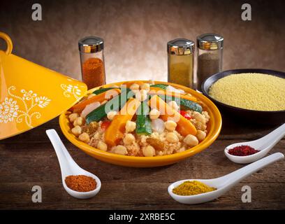 Vegetable tagine with cous cous and spices on wooden table. Stock Photo