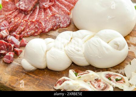 Mozzarella shaped braid on cutting board with salami and cheese. Stock Photo