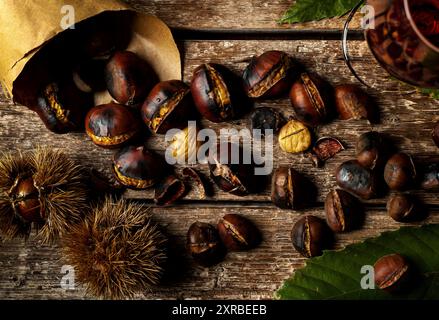 Top view of Roasted chestnuts in paper cone on wooden table. Stock Photo
