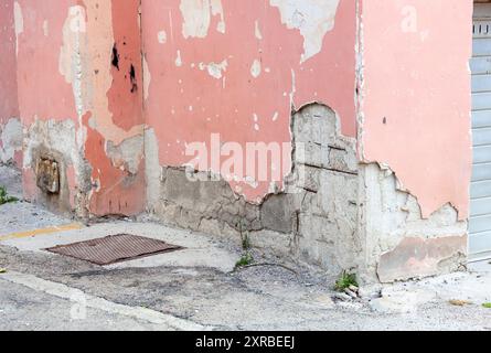 Wall of an old building with ruined plaster and cracks in the concrete. Stock Photo