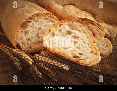 Homemade Italian bread with ears of wheat on wooden table. Stock Photo