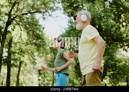 Senior couple listening to music via wireless headphones while running Stock Photo