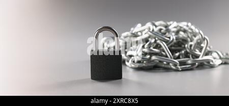 Padlock and metal chains on a gray background Stock Photo