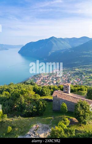 Aerial view of the small church of San Defendente dominating Lake Iseo in summer, Solto Collina, Iseo Lake, Bergamo district, Lombardy, Italy, Stock Photo