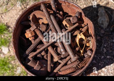 Rusty and weathered old metal pail full of rusty bolts, screws, and hardware Stock Photo